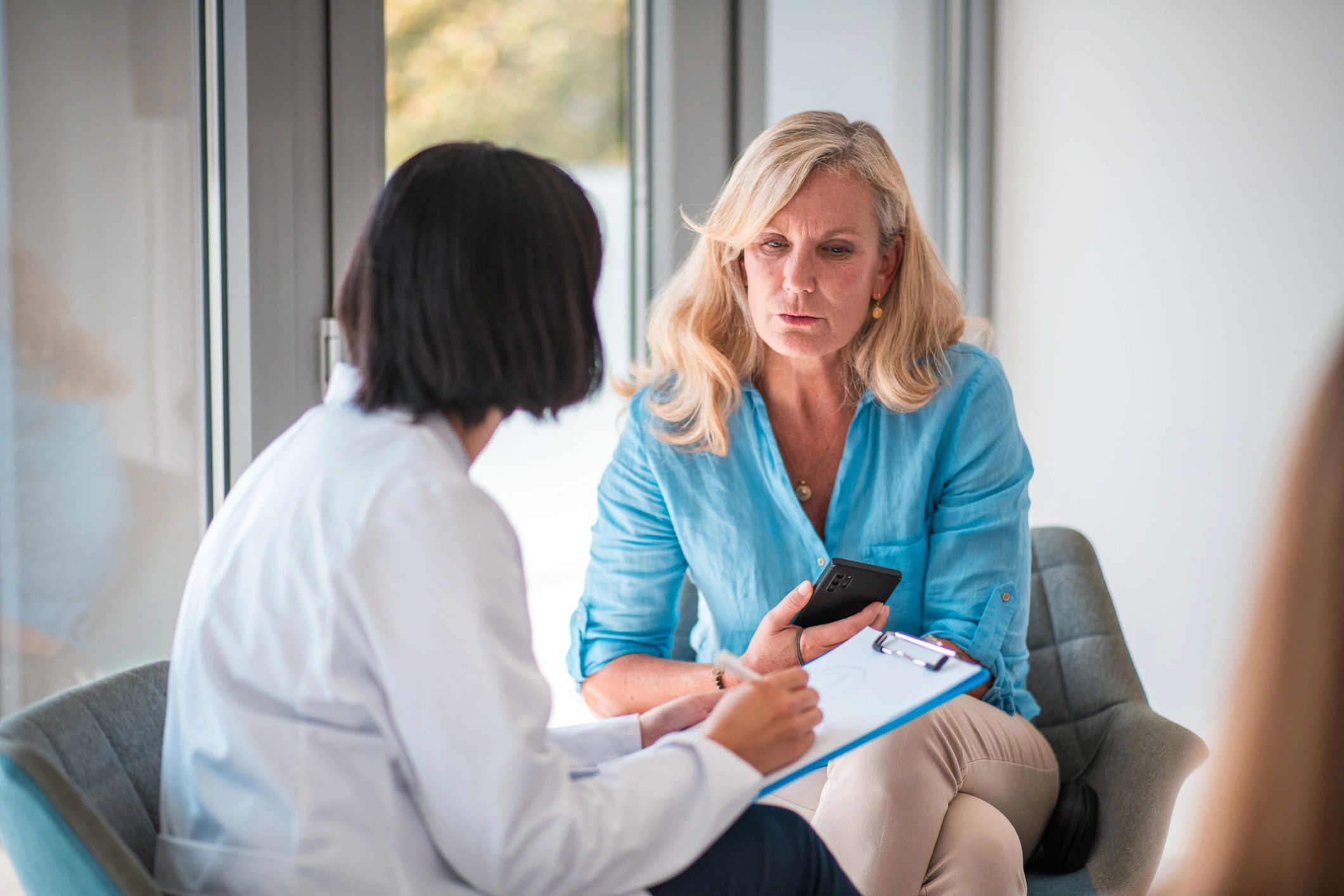 Mature Caucasian Female Patient and Asian Female Doctor in Doctor's Office
